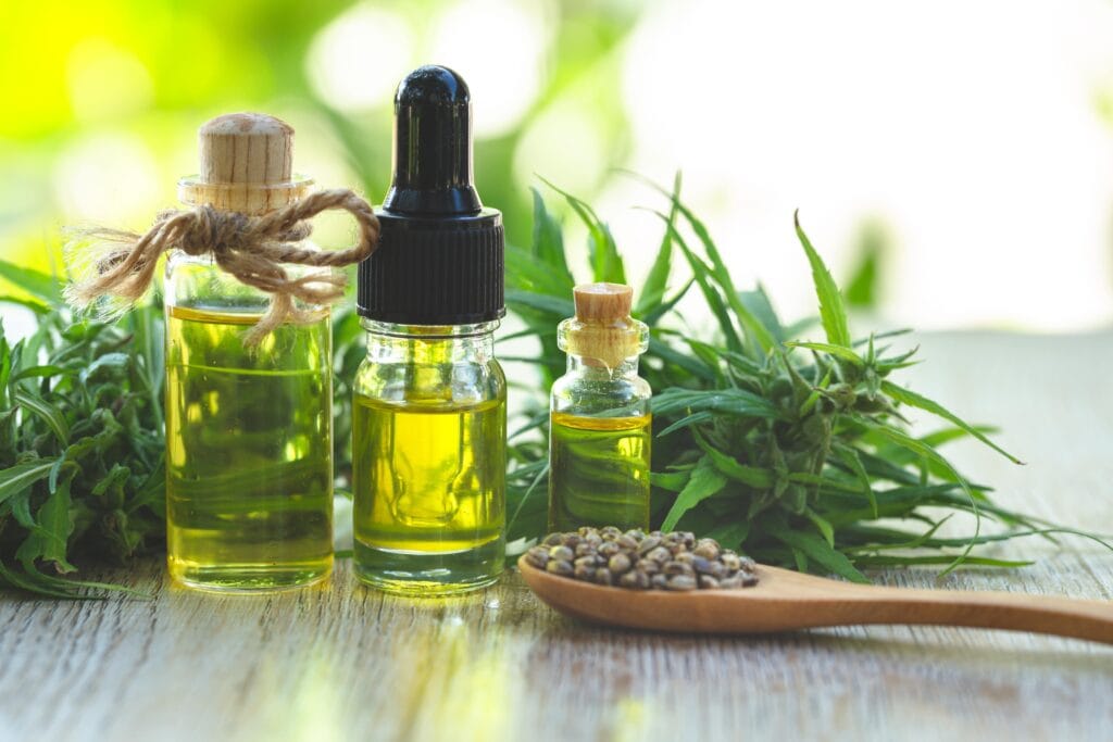 CBD oil in jars, cannabis plant, seeds in spoon